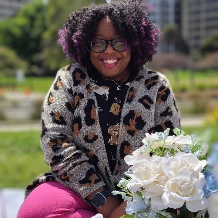 Melanie Knight smiling, holding flowers in a sunny park